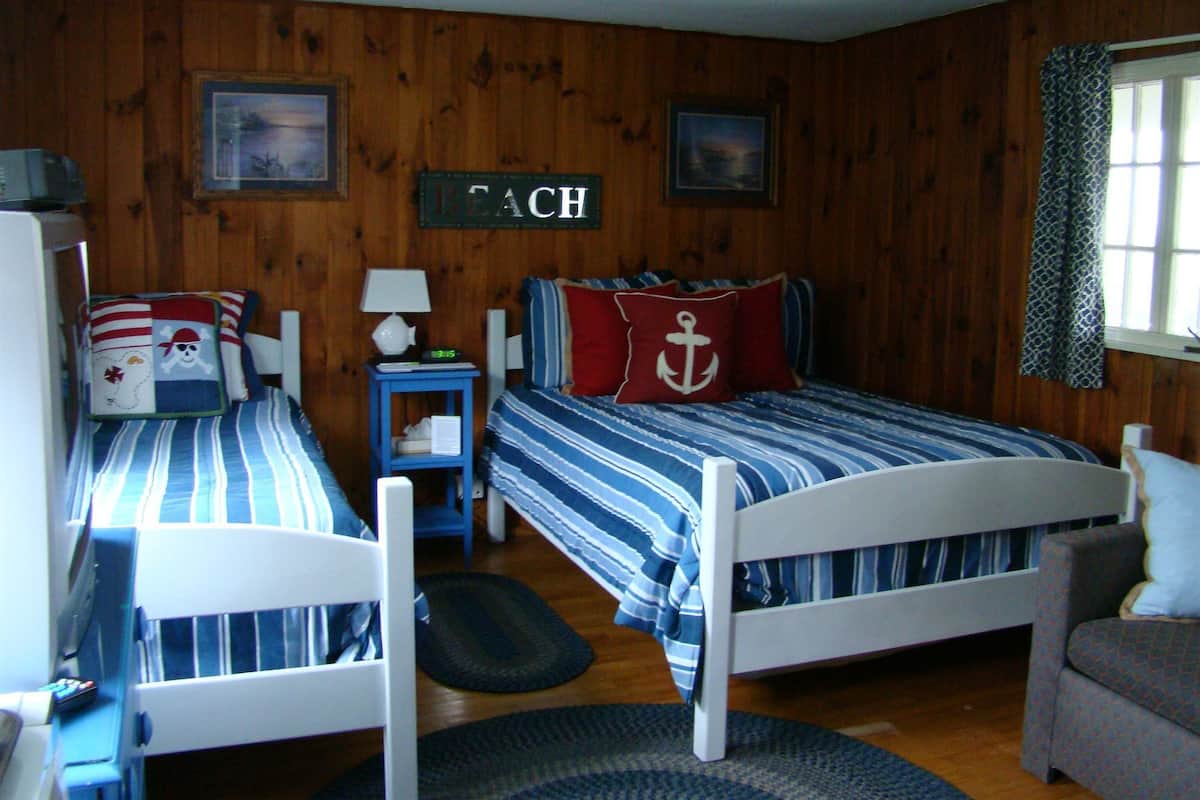 A cabin-style room with two single beds, a small table, and a chair.