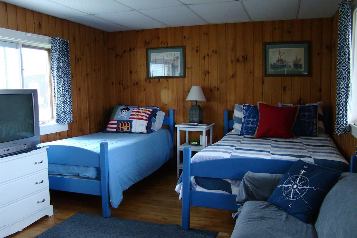 A room with two beds, a television, and a dresser.