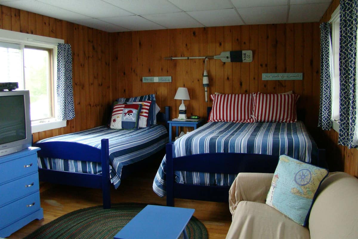 A room with two beds, a TV, a lamp, and a map pillow.
