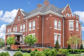 Stunning historic building with a central entrance, covered porch, and clock tower.