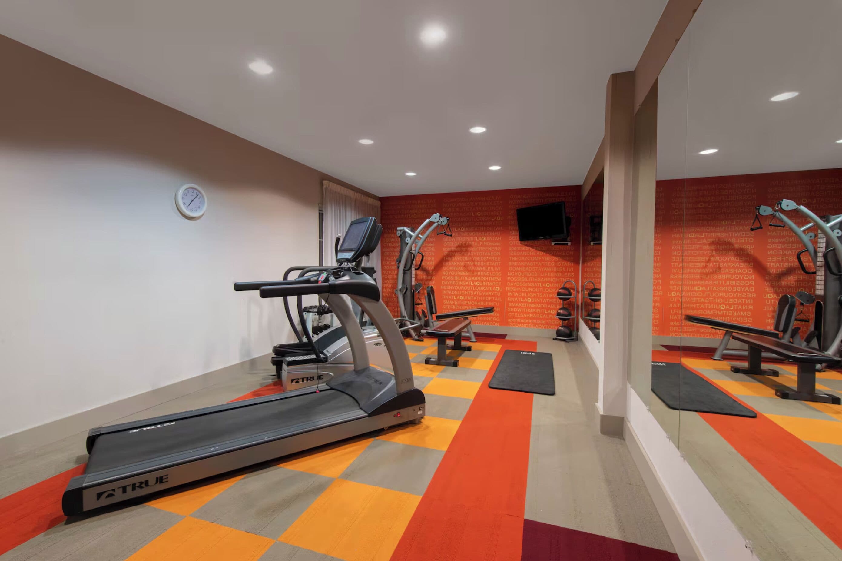 Un gimnasio con cintas de correr, elípticas y bancos de pesas.