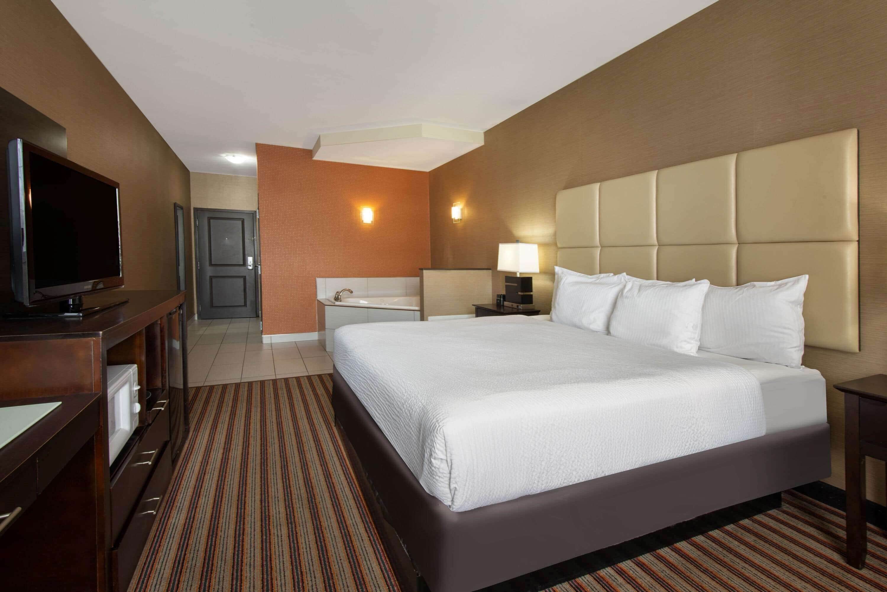 A hotel room with a large bed, a TV, a bathroom, and a desk.