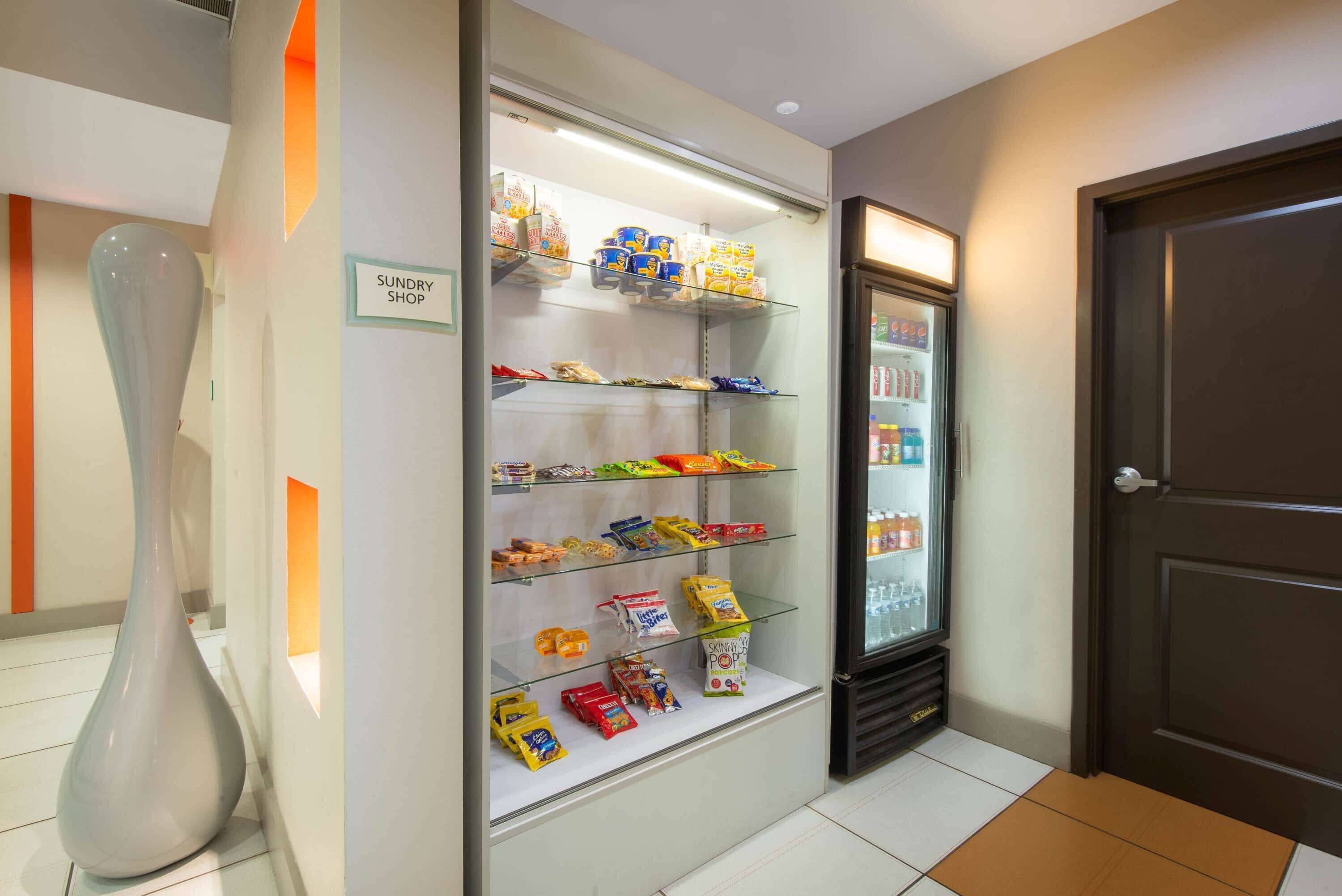 Een winkel met rekken vol snacks en een koelkast met drankjes.