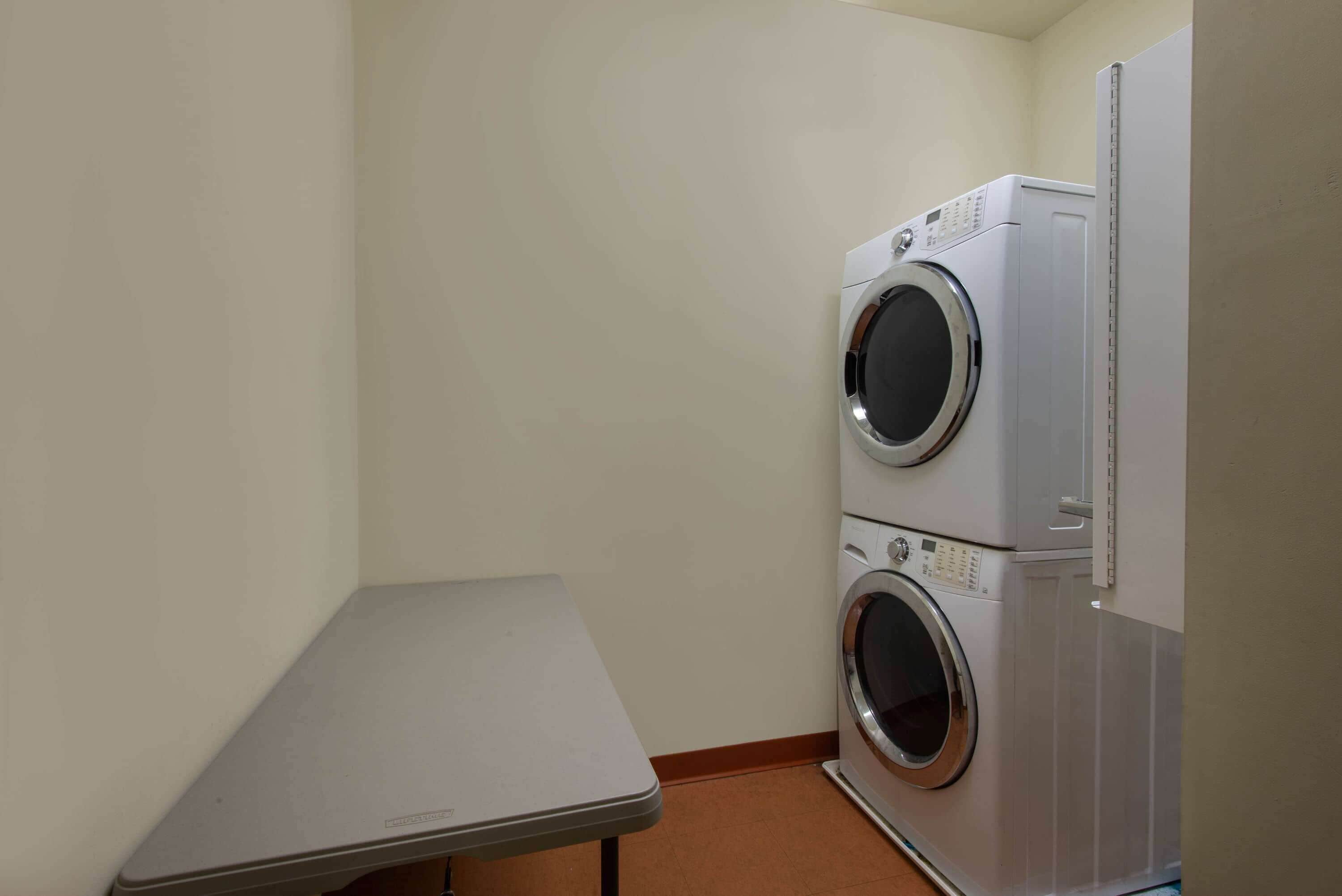 A small laundry room with a washing machine and dryer stacked on top of each other.