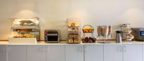 A breakfast bar with a self-serve coffee station, a toaster, and various food containers.