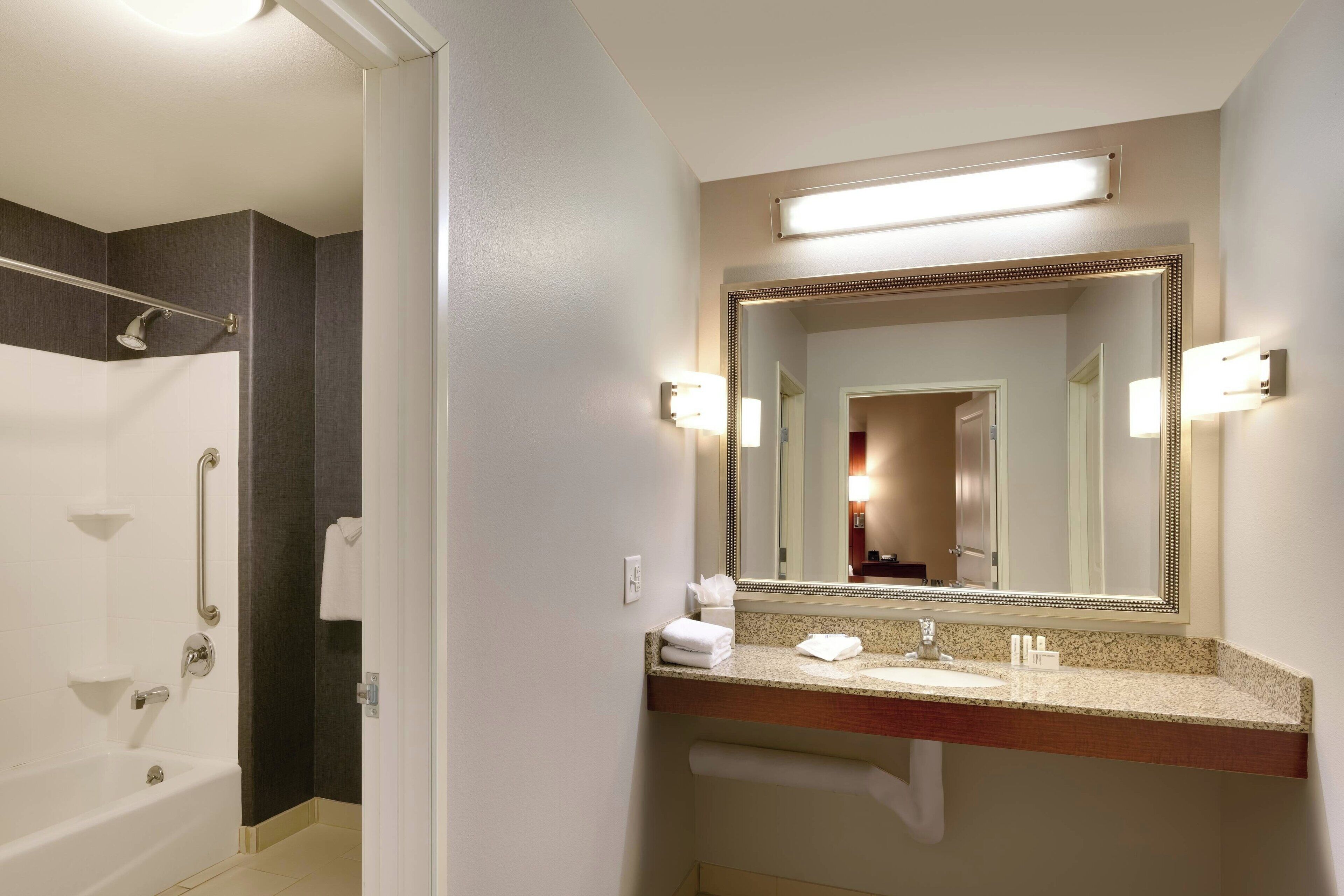 Un baño con bañera, lavabo, espejo y toallero.
