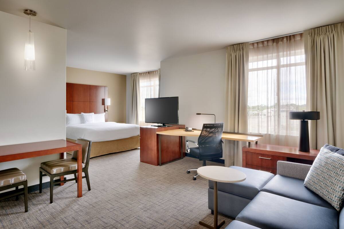 Une chambre d’hôtel équipée d’un lit, d’un bureau, d’une chaise, d’une télévision et d’un canapé.
