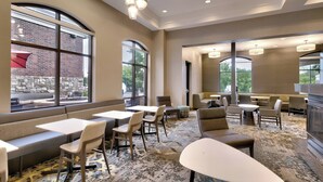 Een moderne hotellobby met zithoeken, grote ramen en een kamerbreed tapijt met een patroon.