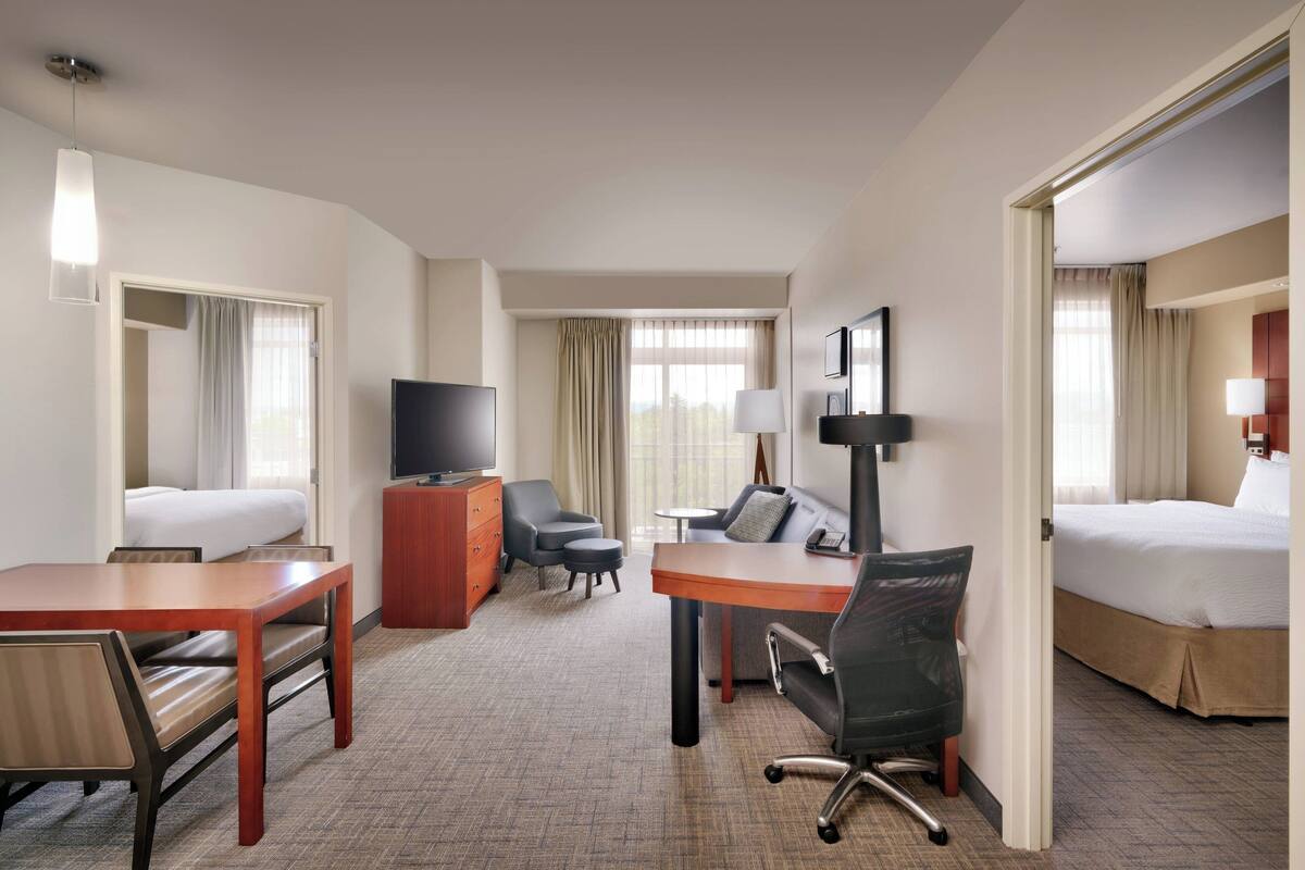 Une chambre d’hôtel avec un lit, un bureau, une chaise, une télévision et une lampe.