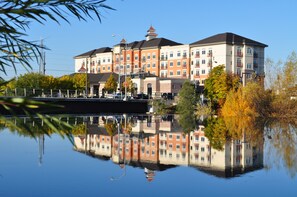 Een meerlaags hotel met een weerspiegeling in het water, met een combinatie van rode en witte gevels, en een opvallende centrale toren.