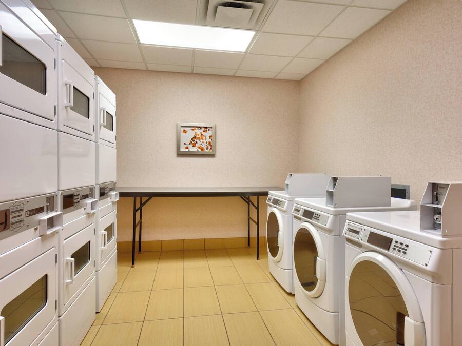 A laundry room with stacked dryers and a washing machine.