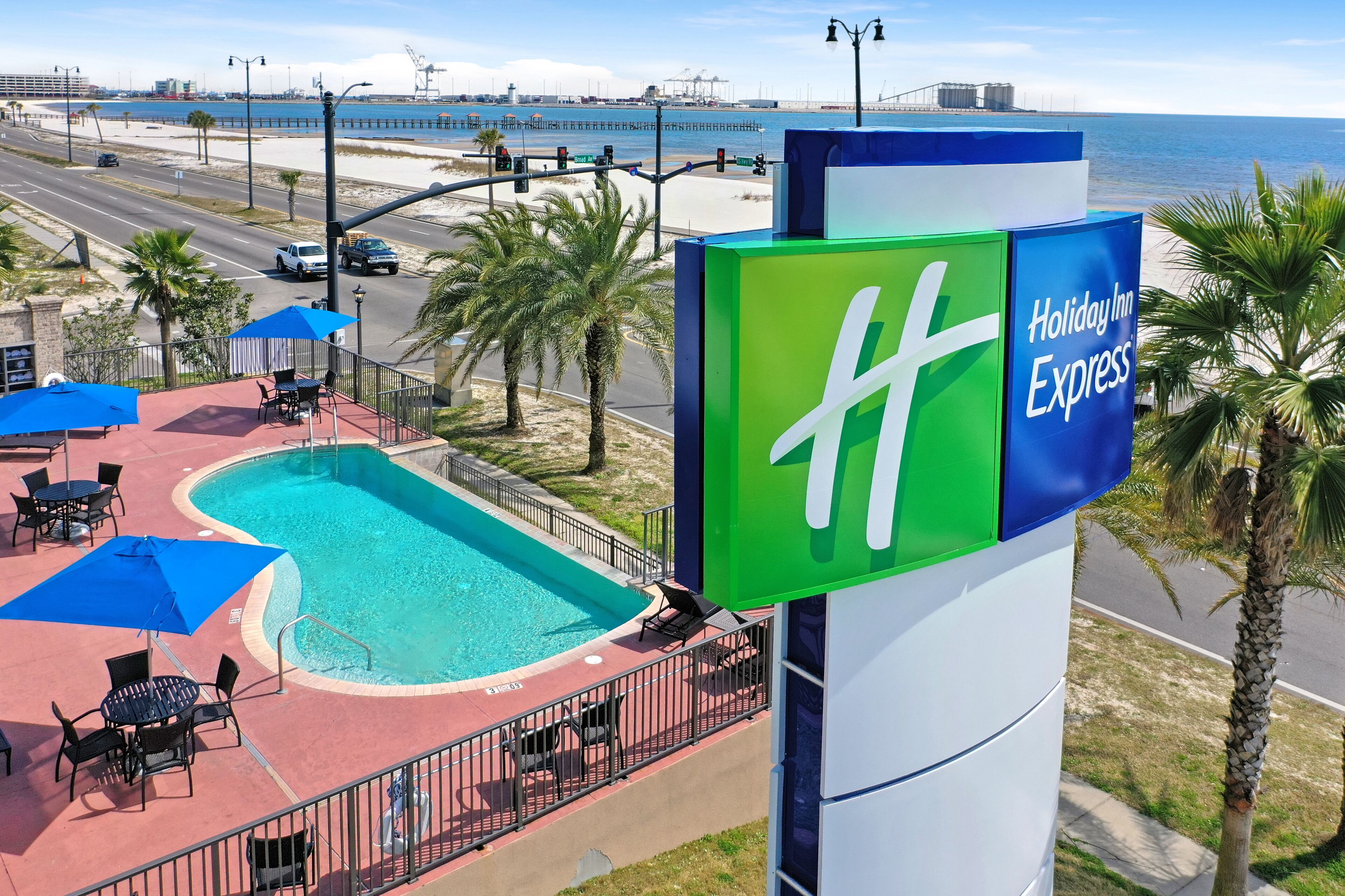 A Holiday Inn Express sign with a pool area featuring lounge chairs and umbrellas.