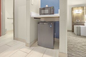 A compact kitchenette with a microwave and refrigerator, a white door, and a blue accent wall.