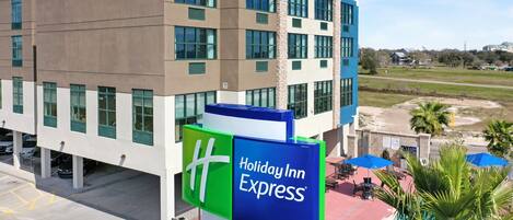 A Holiday Inn Express building with a clear view of the parking area and a pool with umbrellas.