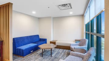 A modern room with a blue sofa, a wooden coffee table, and two armchairs.