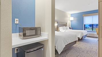Una habitación de hotel con una cama, un microondas y un refrigerador.