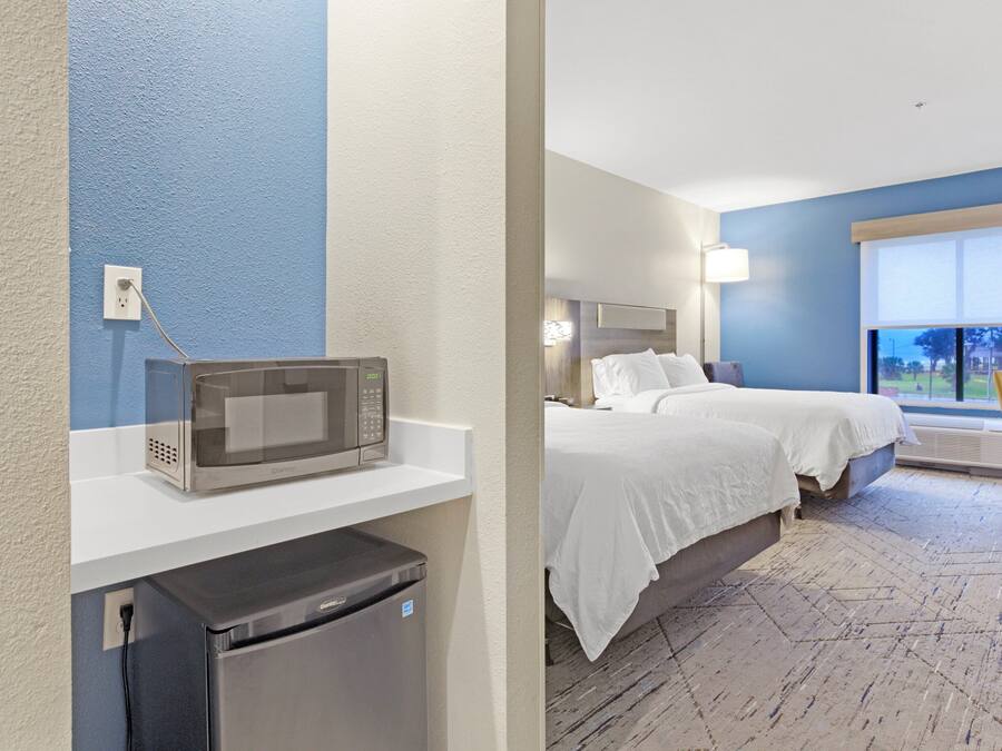 Una habitación de hotel con una cama, un microondas y un refrigerador.