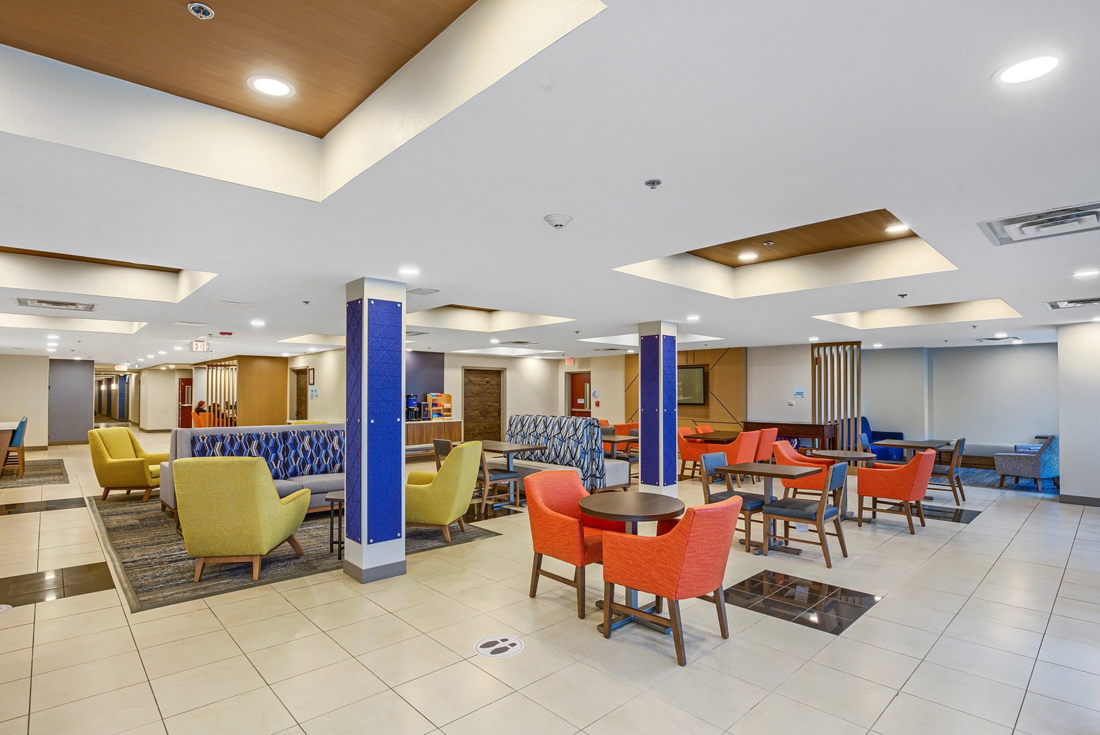 Eine moderne Hotelhalle mit Sitzbereichen, einem Empfangstresen und einer Treppe.