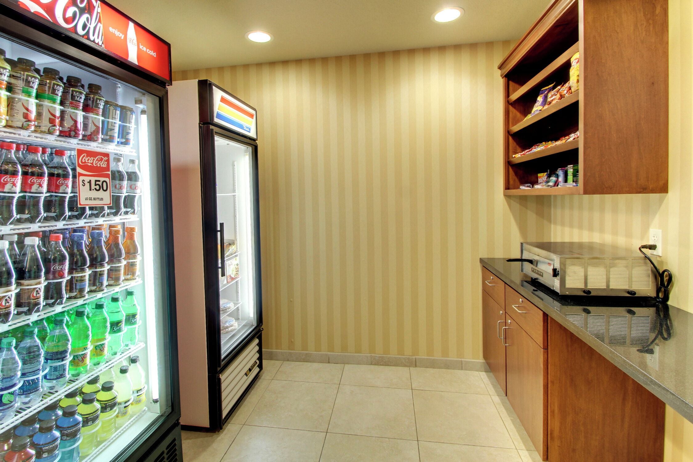 A kitchen area with a refrigerator stocked with beverages, a microwave, and wooden cabinets.