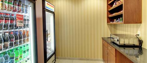 A kitchen area with a refrigerator stocked with beverages, a microwave, and wooden cabinets.