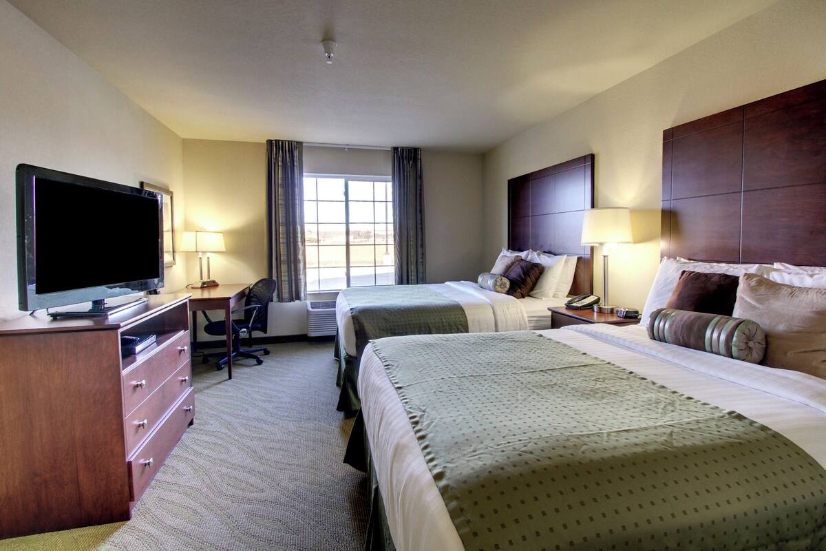A hotel room with a bed, a desk, a television, and a window.