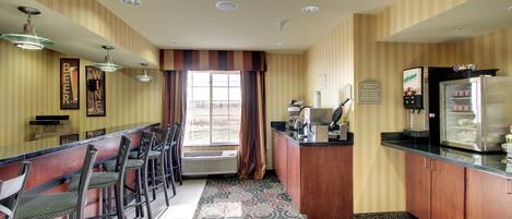 A hotel bar with striped wallpaper, a patterned carpet, and a window with curtains.