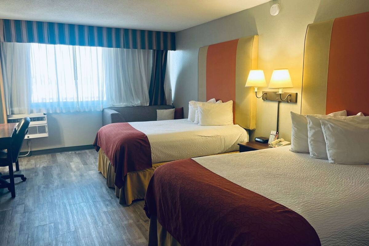 Ein Hotelzimmer mit zwei Betten, einem Schreibtisch und einem Stuhl.