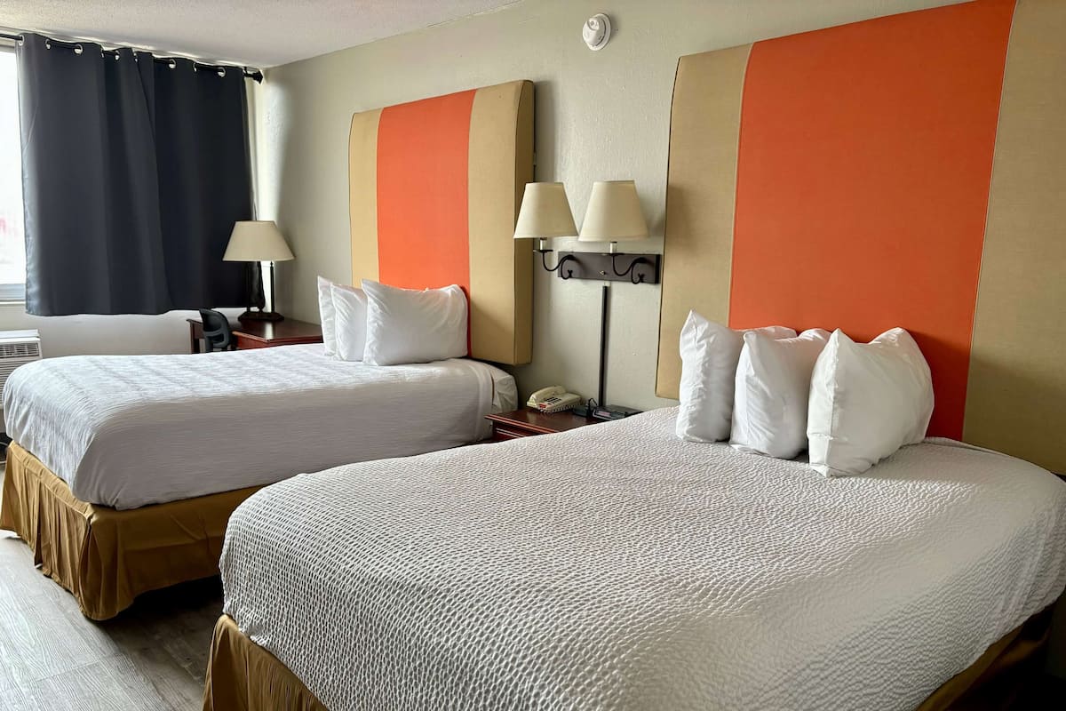 Ein Hotelzimmer mit zwei Betten, einem Schreibtisch, einer Lampe und einem Telefon.