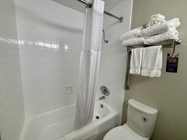 A bathroom with a bathtub, a toilet, and a towel rack with folded towels.