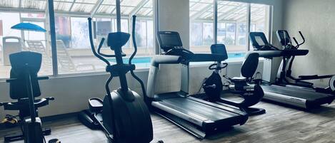 A gym with cardio machines, a treadmill, and a rowing machine.