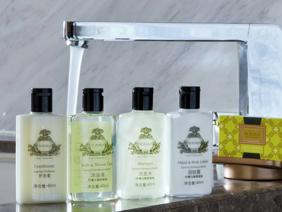 Quatro frascos de produtos AGRARIA e uma caixa de sabonete de capim-limão sobre um balcão de mármore.