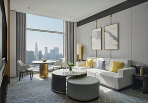 Une chambre d’hôtel moderne dotée d’une grande fenêtre, d’une table de salle à manger ronde, d’un canapé et d’une table basse.
