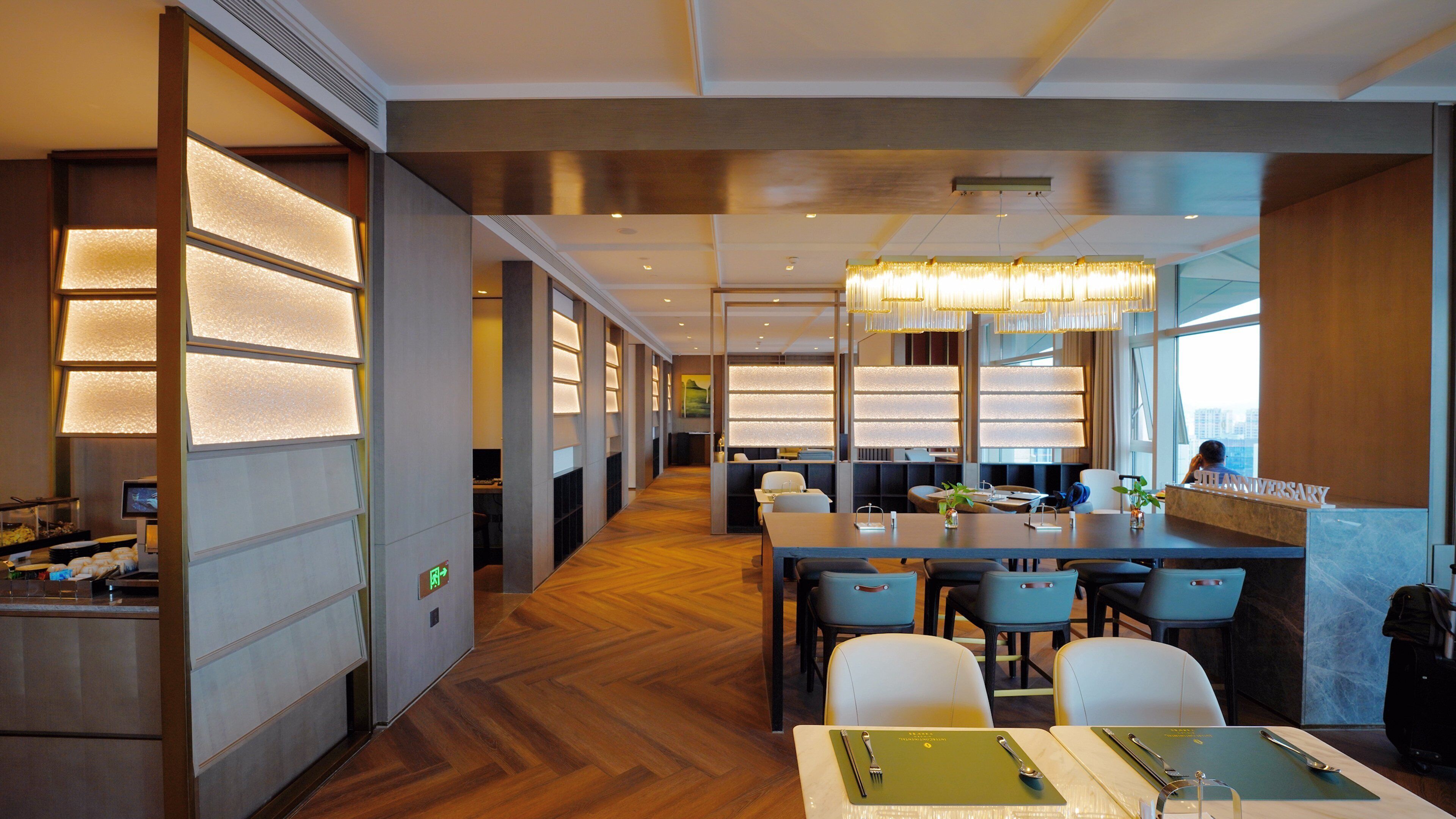 A modern hotel lobby with a long reception desk, comfortable seating, and a view of the city.
