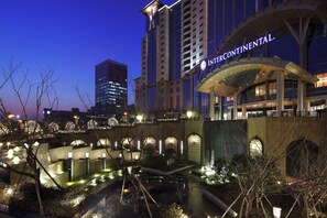A hotel with a modern architectural design, featuring a prominent entrance and a landscaped courtyard with water features. - The Azure Ningbo, Vignette Collection by IHG (Ningbo)