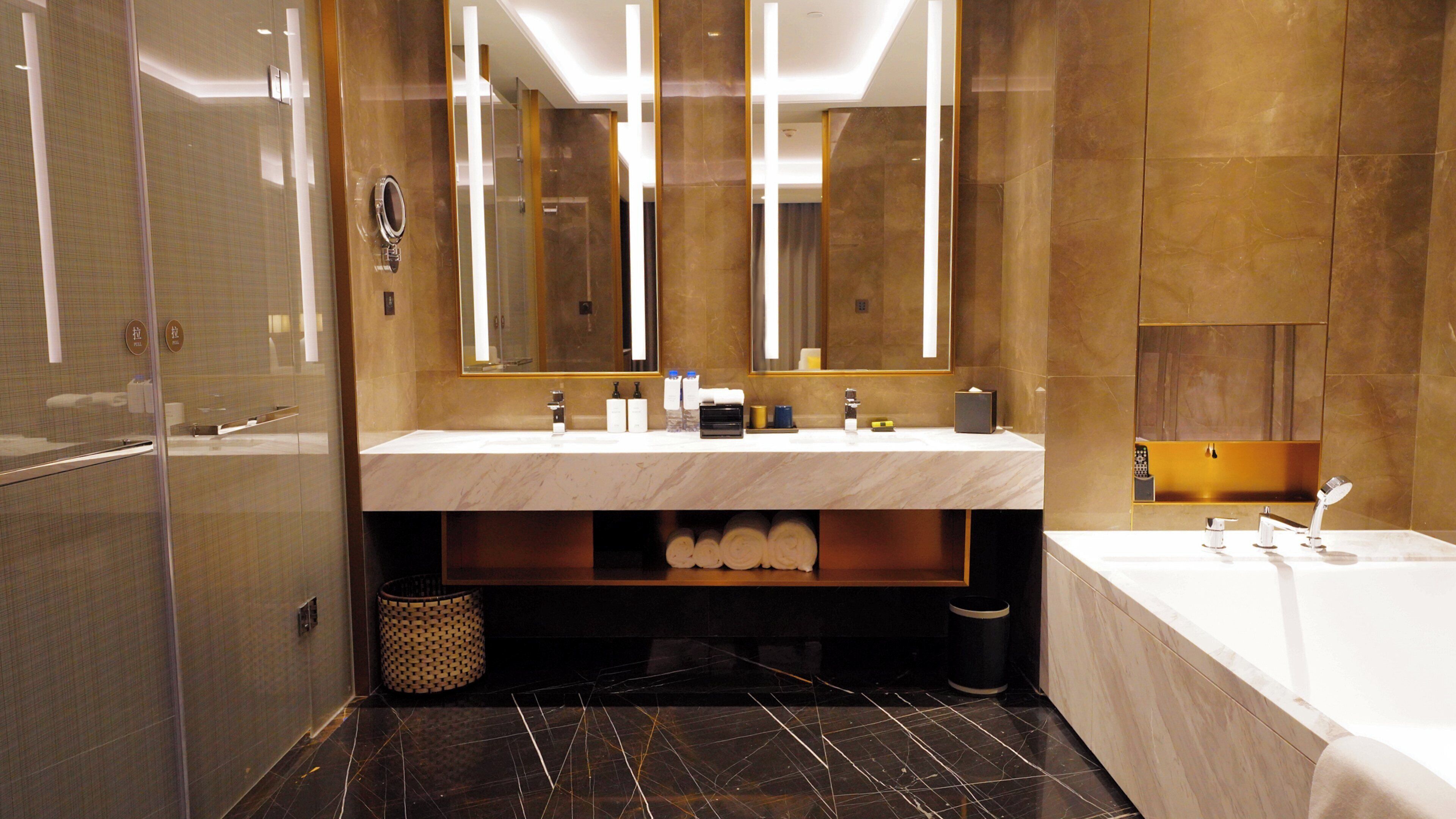 A modern bathroom with a marble sink, a large mirror, a bathtub, and a shower area.