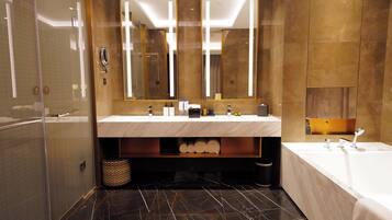 A modern bathroom with a marble sink, a large mirror, a bathtub, and a shower area.