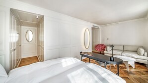 A hotel room with a large bed, a small table, a sofa, and a mirror. - BLUME. - Baden Hotel & Restaurant (Baden)
