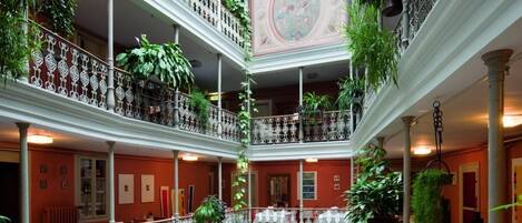 A multi-level atrium with balconies, potted plants, and a central fountain.