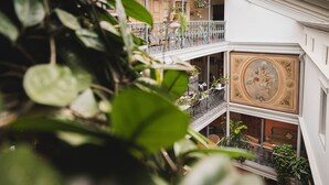 A multi-level building with balconies, plants, and a decorative ceiling. - BLUME. - Baden Hotel & Restaurant (Baden)