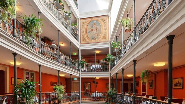 A multi-level atrium with a central fountain, balconies with plants, and a classic architectural ceiling. - BLUME. - Baden Hotel & Restaurant (Baden)