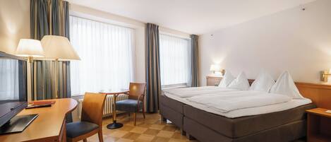 Una habitación de hotel con cama, escritorio, silla y televisor.