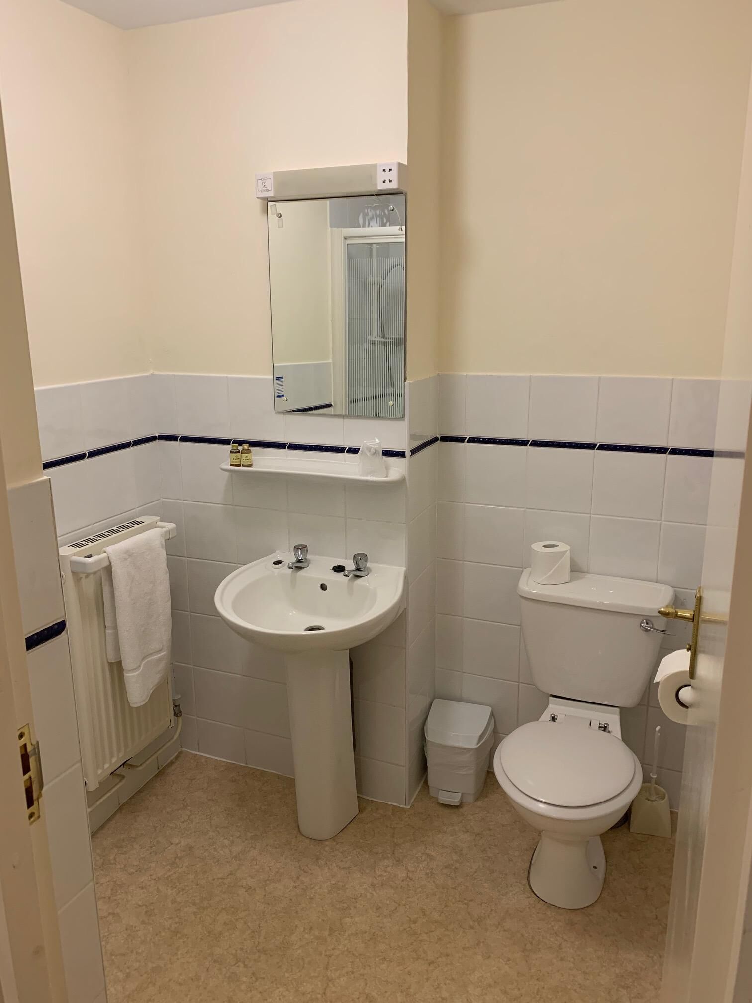 A small bathroom with a sink, toilet, and a mirror.