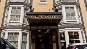 Un hotel con fachada clásica, que presenta ventanas salientes y una entrada destacada.