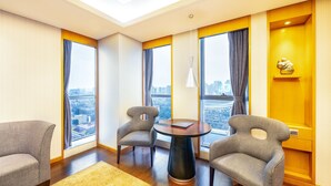 A modern hotel room with a large window offering a city view, a round table with two chairs, and a sofa. - Lia Chengdu Hotel (Chengdu)