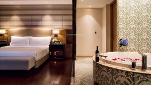 A hotel room with a large bed, a sitting area, a bathroom with a bathtub, and a decorative wall. - Lia Chengdu Hotel (Chengdu)