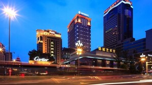 A cityscape at dusk with illuminated buildings including a hotel named 'Cartier' and a building with 'PICC' signage. - Lia Chengdu Hotel (Chengdu)