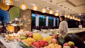 A buffet with a variety of fruits and pastries, a chef in uniform, and hanging pendant lights. - Lia Chengdu Hotel (Chengdu)