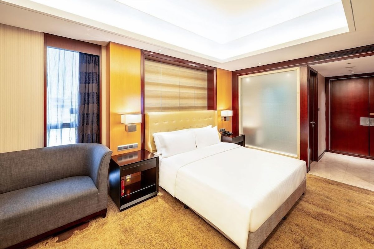 Ein Hotelzimmer mit einem Bett, einem Sofa, einem Nachttisch und einer Wandlampe.