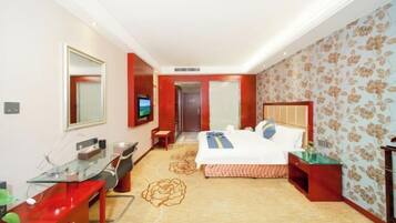 Ein Hotelzimmer mit Bett, Schreibtisch, Stuhl, Fernseher und Spiegel.