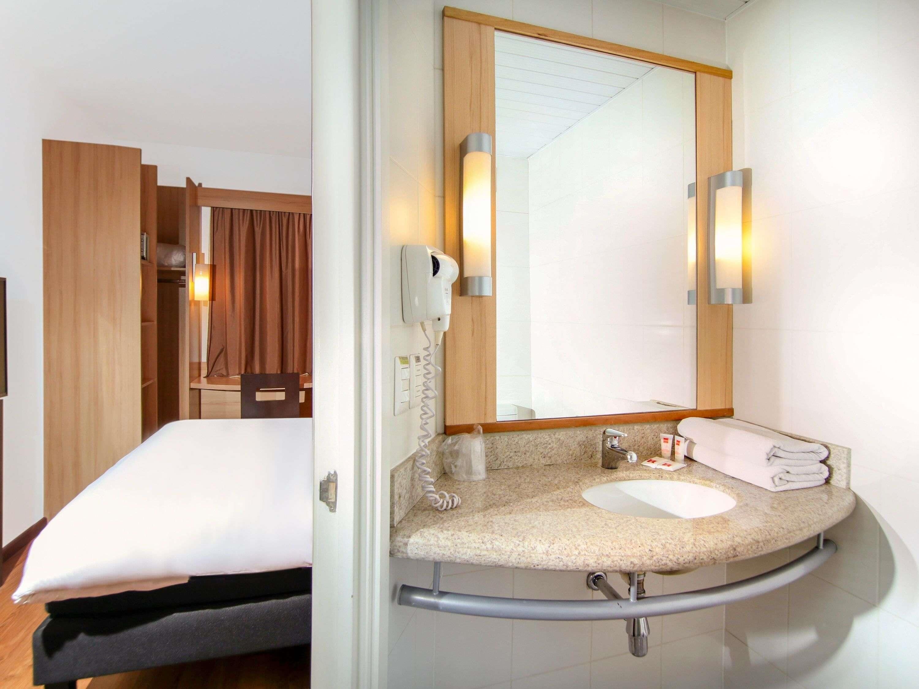 A hotel bathroom with a sink, mirror, towel, and a hairdryer.